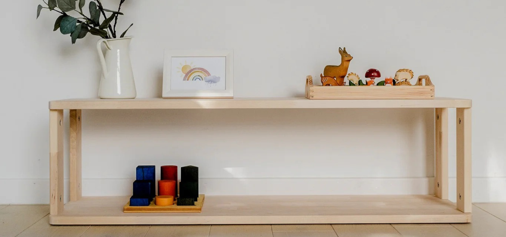 Étagère Montessori en bois clair avec quelques jouets rangés et présentés à hauteur d’enfant