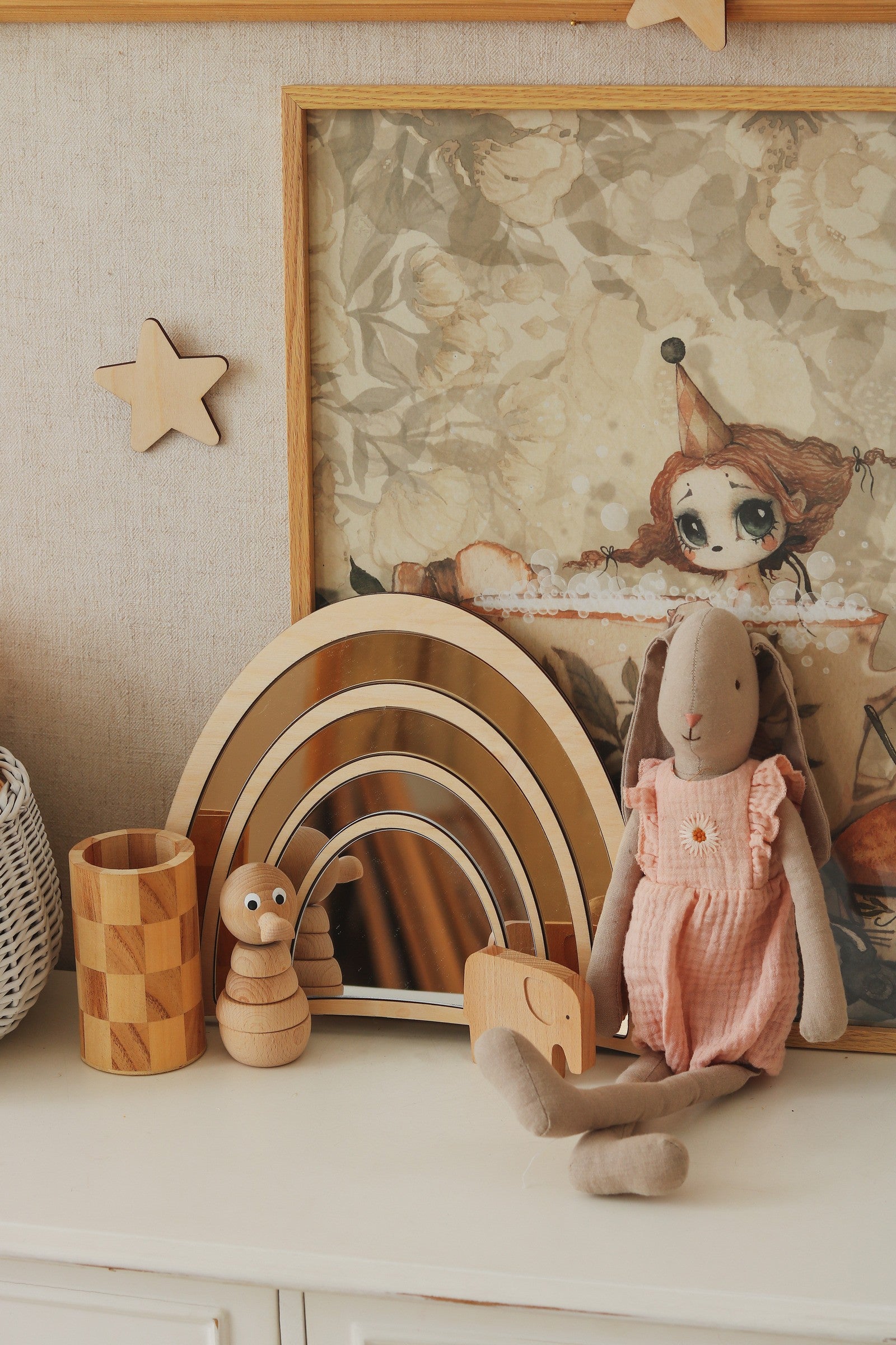 Décor de chambre d'enfant avec miroir arc-en-ciel en bois et acrylique aux tons naturels, accompagné d'une poupée lapin en tissu, d'étoiles murales et d'accessoires en bois, accessoire de décoration intérieure pour chambre d'enfant douce et chaleureuse, idéal pour les mots-clés miroir arc-en-ciel, chambre enfant, décor en bois et style Montessori.
