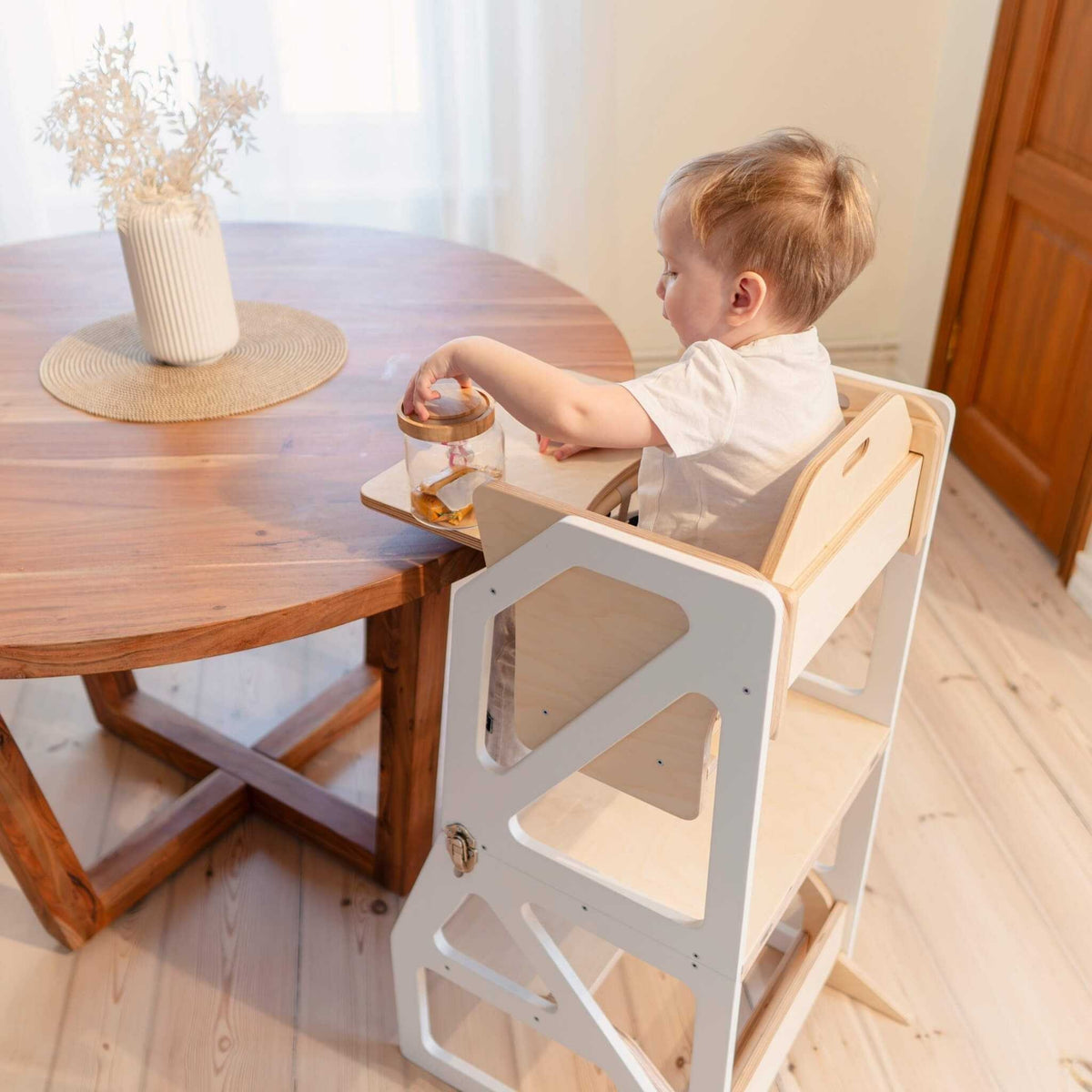 Tour d’observation Modustep avec chaise haute – Un jeune enfant assis à une table avec un vase
