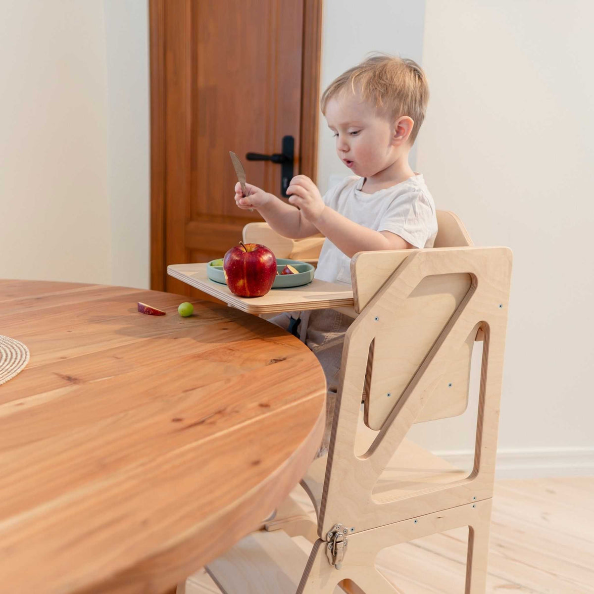 Tour d’observation Modustep avec chaise haute – Un jeune garçon assis à table avec des pommes