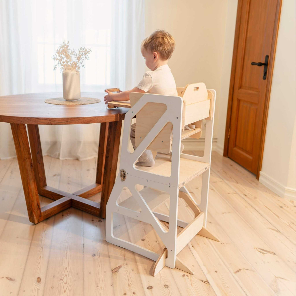 Tour d’observation Modustep avec chaise haute – Un petit garçon assis à une table avec une plante dans un vase