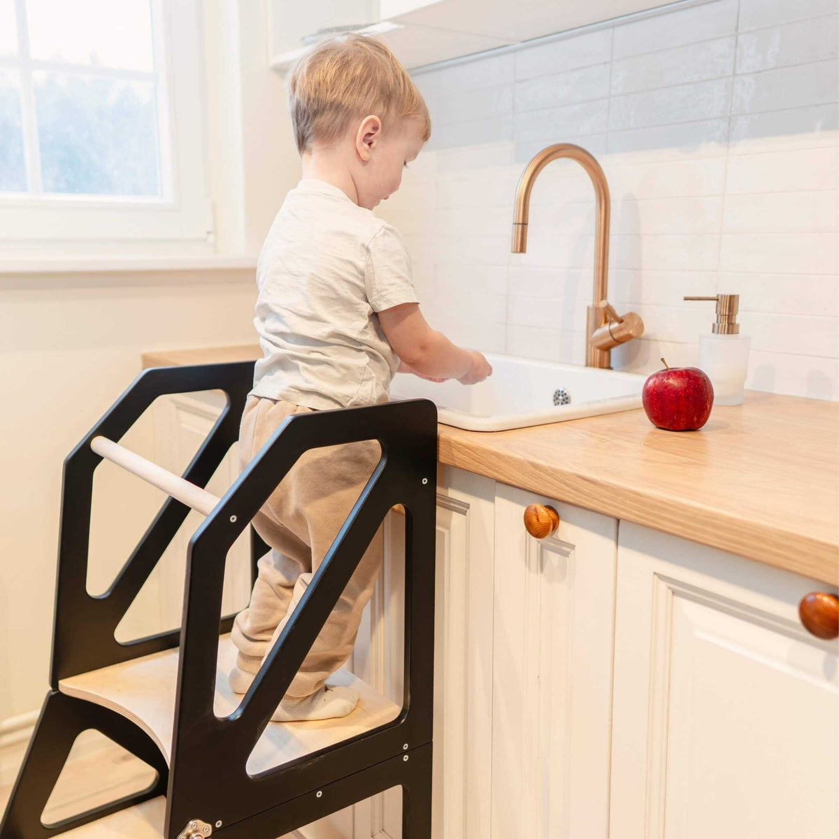 Tour d’observation Modustep avec chaise haute – Un jeune garçon debout sur une chaise devant un lavabo