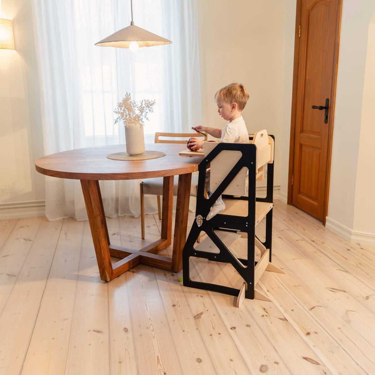 Tour d’observation Modustep avec chaise haute – Un jeune enfant assis à une table dans une chambre
