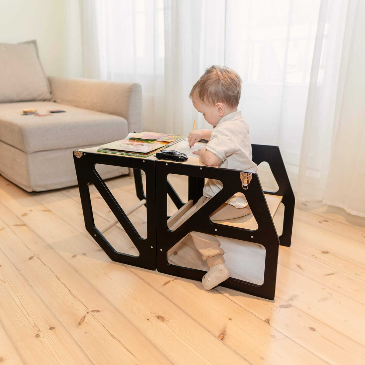Tour d’observation Modustep avec chaise haute – Un petit enfant assis à une table dans une chambre