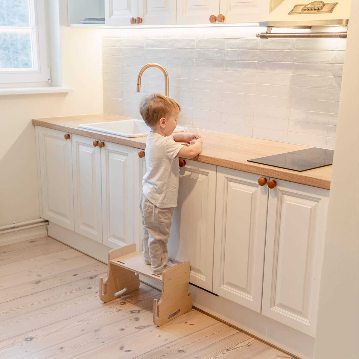 Tour d’observation Modustep avec chaise haute – Un petit enfant debout sur un tabouret d'escalier dans une cuisine